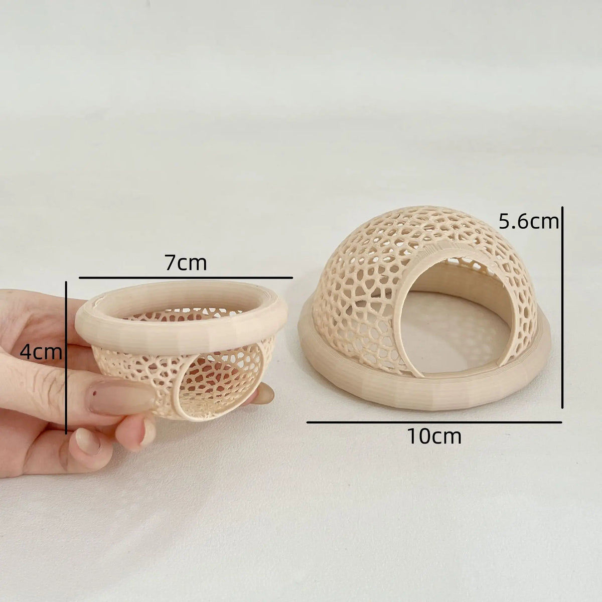 A hand holds a beige, perforated hammock designed for betta and shrimp aquarium decoration.