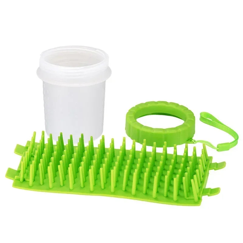 A bright green silicone pet paw cleaner tool next to a white plastic container.