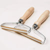 A silver manual lint remover brush with wooden handles is shown against a white background.
