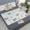 A waterproof cartoon bed protector pad featuring cute animal characters and a teddy bear on a gray bed.
