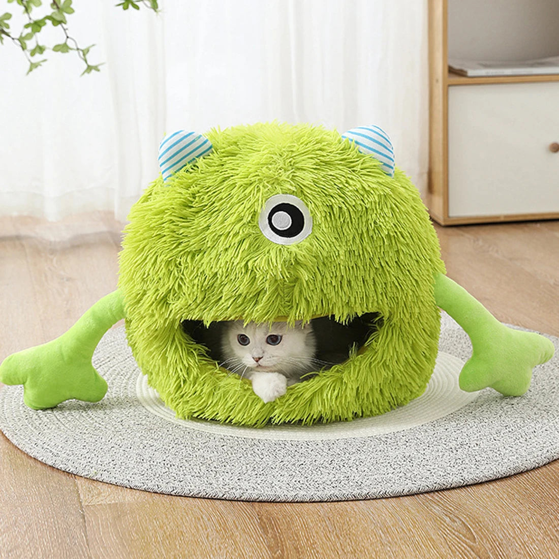 A bright green plush monster cave bed with large eyes and striped ears, designed for a small pet.