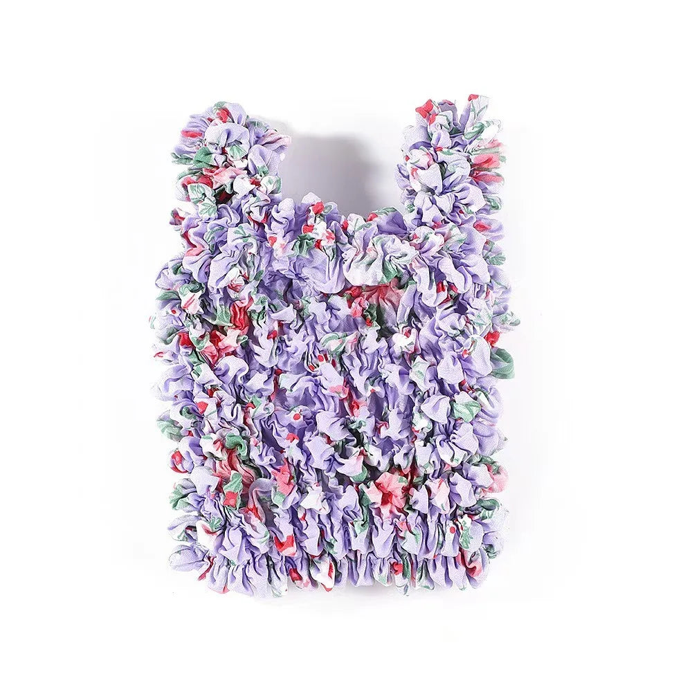 A dense, reusable foldable bubble shopping bag made of ruffled purple and pink fabric.