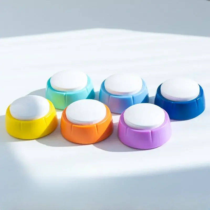 A collection of colorful, round pet training buttons for dog and cat communication arranged on a white surface.