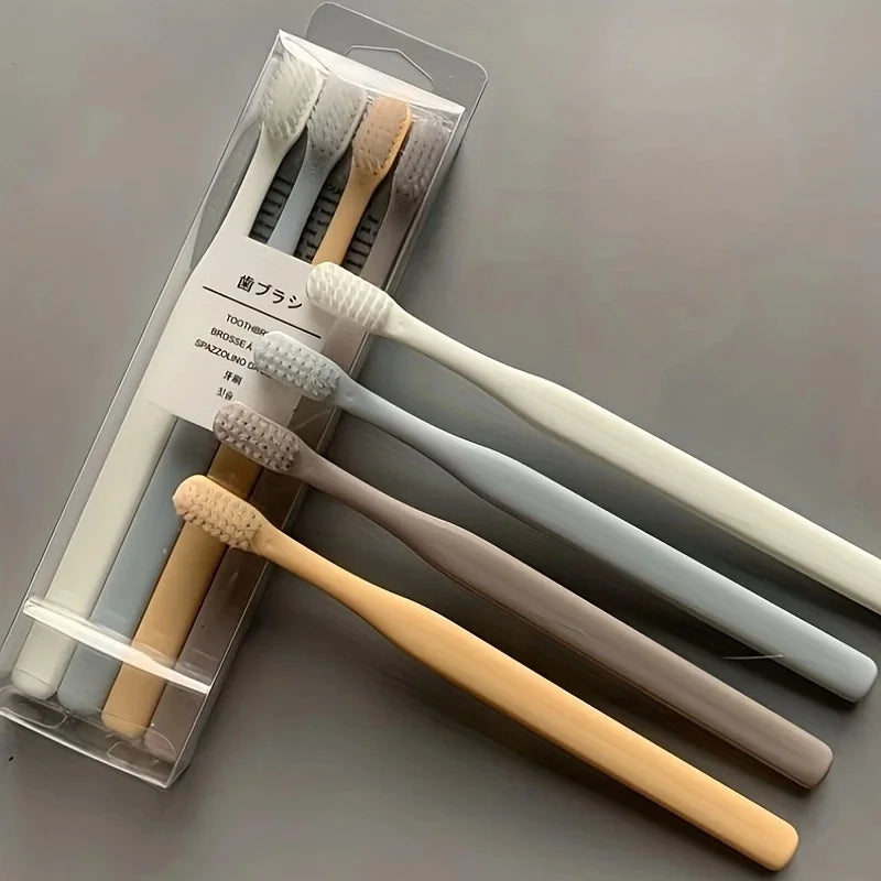 A clear plastic case holds a set of four soft-bristle travel toothbrushes in various natural wood and white colors.
