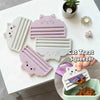 A pink cat food pouch squeezer tool is shown next to a white version and some cat treats on a white surface.