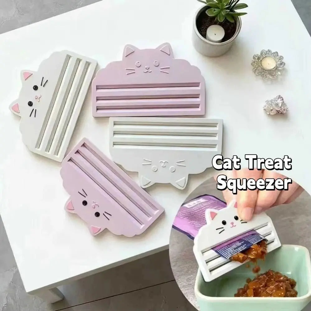 A pink cat food pouch squeezer tool is shown next to a white version and some cat treats on a white surface.