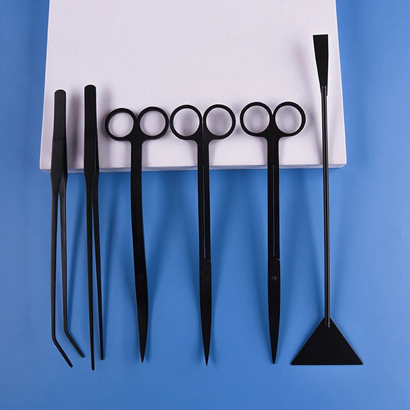 A set of black stainless steel aquarium plant trimming tools, including various scissors and a specialized trimming tool.
