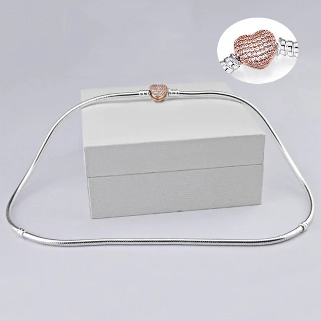 A sterling silver snake chain necklace with a heart charm displayed on a white box.