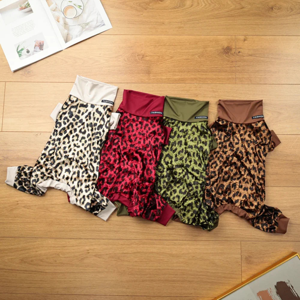 A row of leopard print dog pajamas in various colors, including red, green, and brown, laid out on a wooden floor.