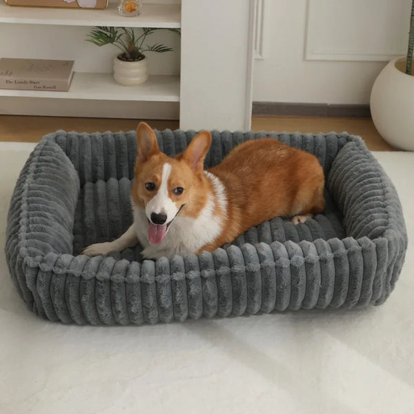 An orange and white dog is lying inside a gray plush pet bed.