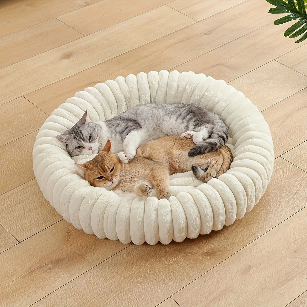 A gray and orange cat is resting inside a round, white, plush pet bed.