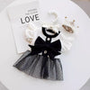 A black and white ruffled dress for a small dog displayed on a white table.