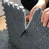 Close-up of a gray, textured fleece pet warming mat being held by a person.