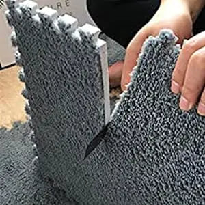 Close-up of a gray, textured fleece pet warming mat being held by a person.