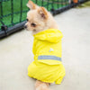 Un chien de couleur beige clair portant un imperméable jaune vif à l'extérieur.