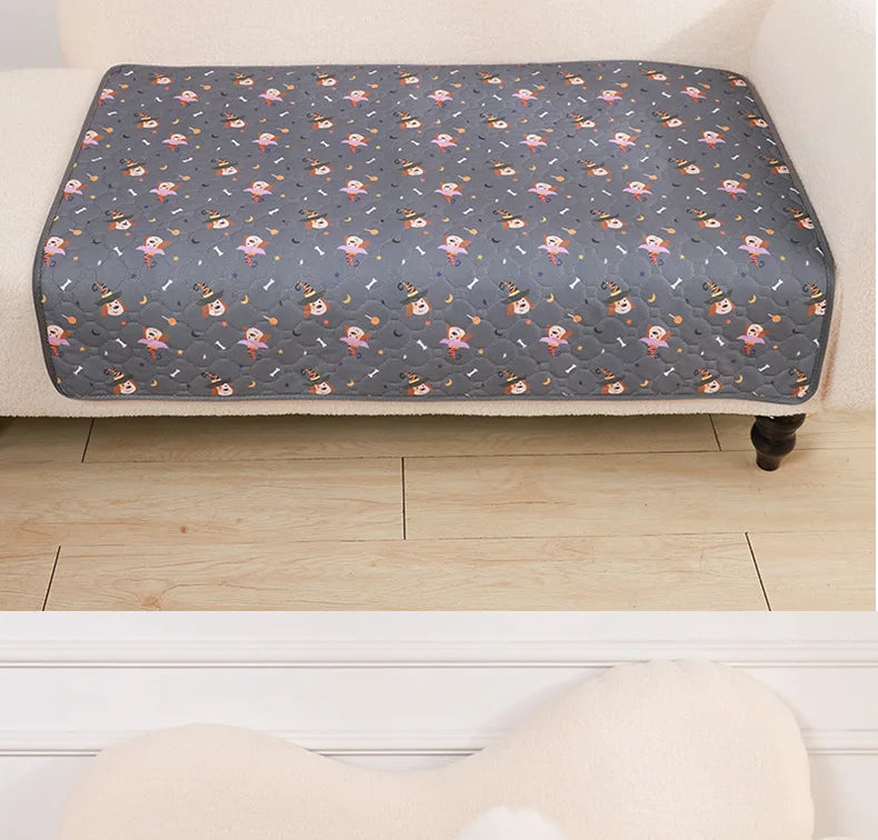 A gray pet pee pad with a repeating pattern of small pink and orange animal figures is placed on a light wooden floor.