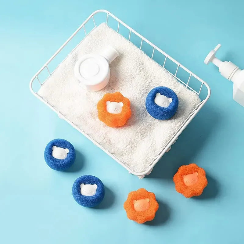 A white rectangular pad holds several orange and blue reusable pet hair and lint removal balls on a light blue background.