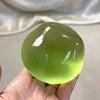 Eine Hand hält eine durchscheinende limettengrüne, weiche Stressball mit weißen Streifen.