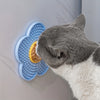 A gray cat licking a blue silicone mat designed for dogs and cats on a light gray surface.