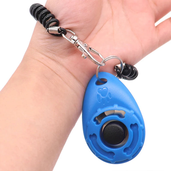 A hand is holding an adjustable pet training clicker with a blue oval body and black nose.