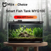 Un aquarium intelligent MYG100 exposé dans un enclos de verre avec une végétation aquatique luxuriante et des roches.