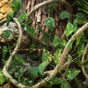 Green artificial reptile vines winding around a tree trunk in a terrarium setting
