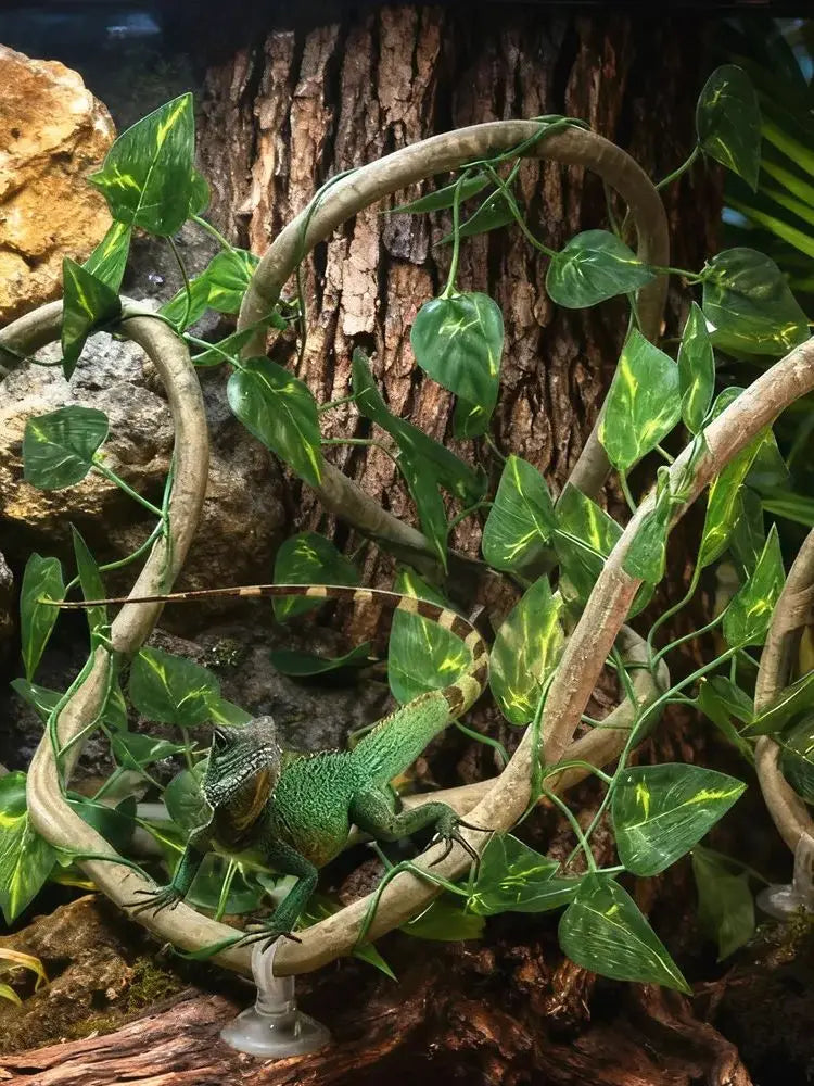 Green artificial reptile vines winding around a tree trunk in a terrarium setting