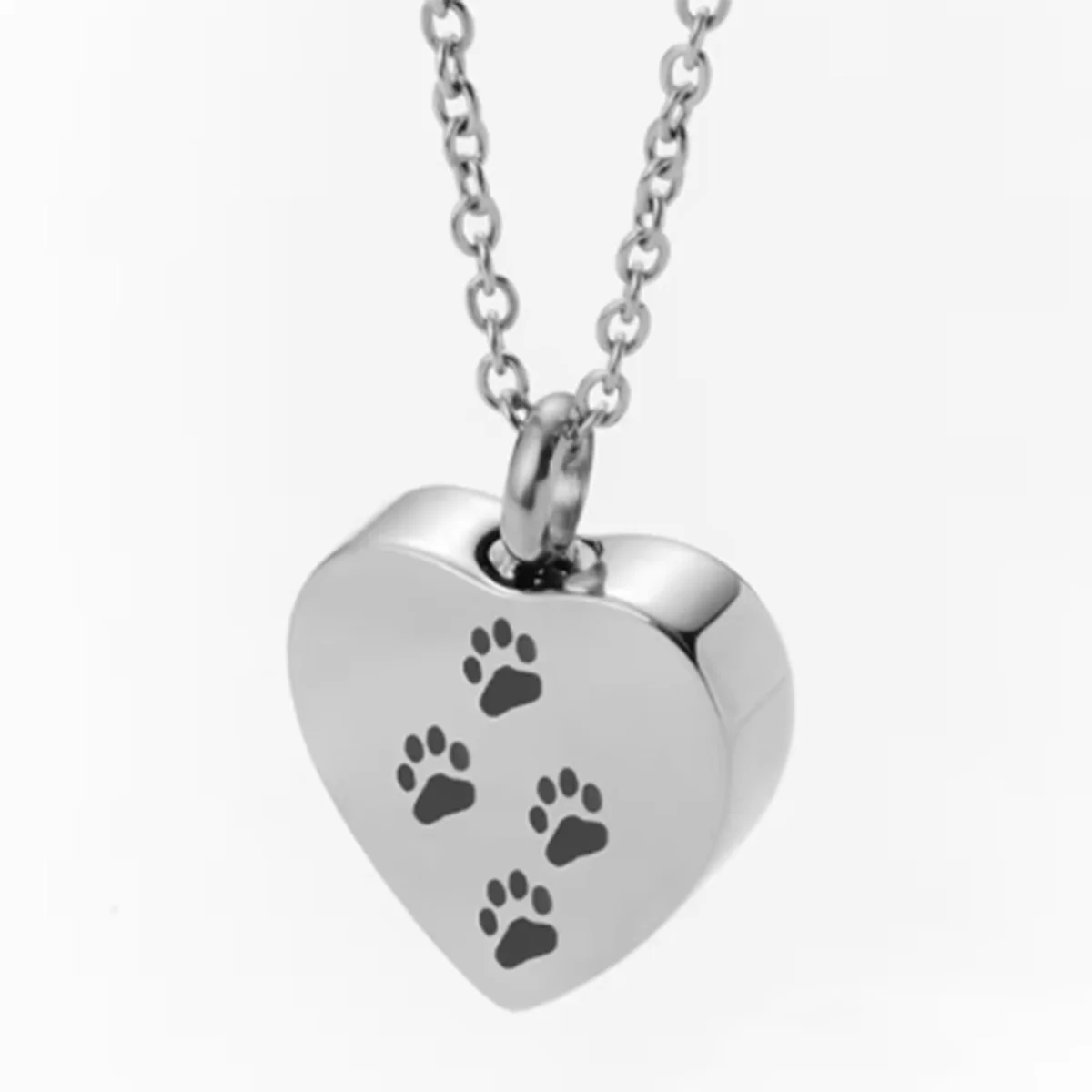 A silver stainless steel heart-shaped necklace featuring four paw prints engraved on the pendant.