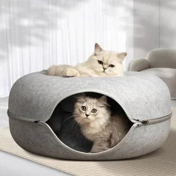 A fluffy white cat is relaxing inside a gray felt cat bed with a tunnel hideaway for two cats.