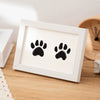 A white wooden photo frame displaying two black paw prints, suitable for a keepsake kit.