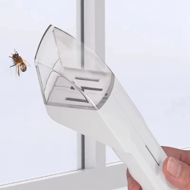 A hand holds a white portable handheld insect catcher, which is positioned near a window where an insect is visible.