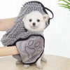 Un chien blanc portant une serviette de bain grise avec motif de patte