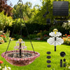 A solar-powered hanging bird bath fountain with a glass bowl and water spouts is suspended in a garden setting.