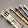 A set of four soft-bristle travel toothbrushes in a clear plastic case with light wood handles.