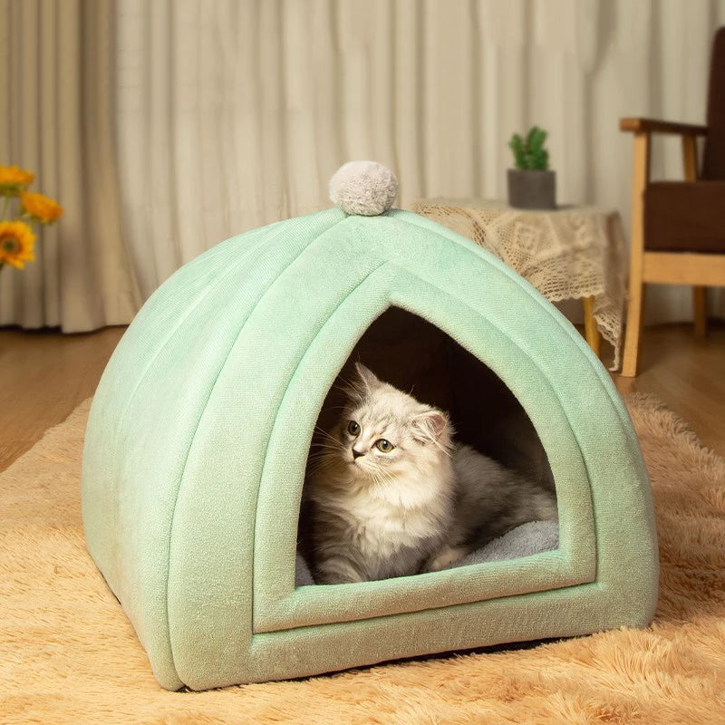 A light green, arched cat bed cave with a fluffy cushion resting on a beige rug.
