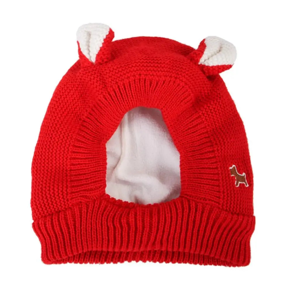 A bright red knit beanie with white ear muffs for dog anxiety and winter warmth