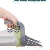 A hand is holding a gray reusable pet litter scoop with a solid, anti-slip handle and a green waste bag.