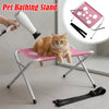 A cat is sitting on a pink pet bathing stand with a grooming nozzle and a separate grooming hammock.