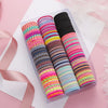 A clear box filled with colorful elastic hair bands in various shades of pink, purple, blue, and green.