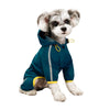 A small, fluffy dog wearing a teal waterproof raincoat with yellow trim and reflective details.