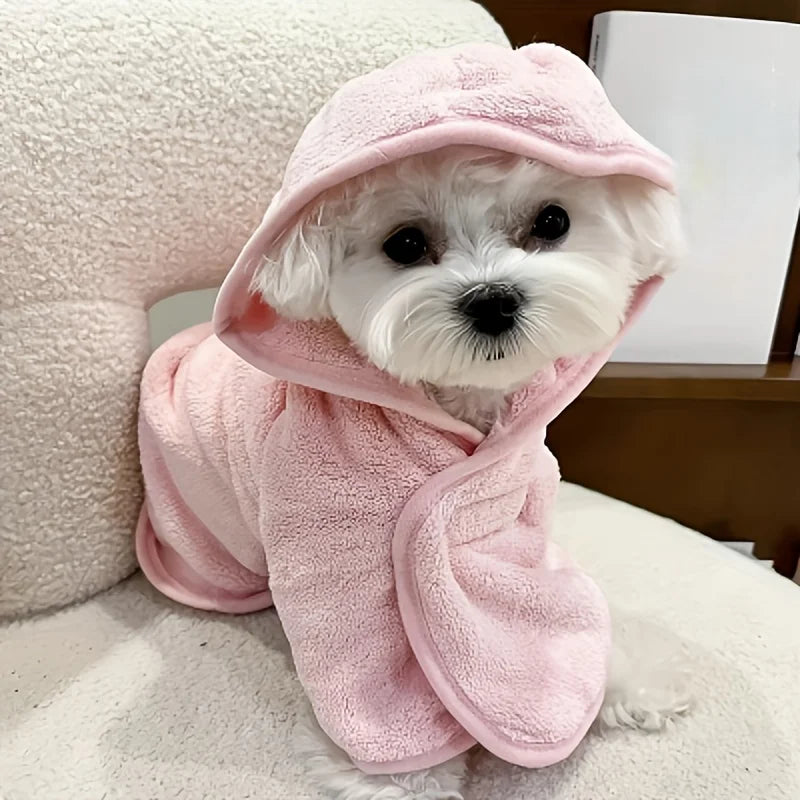 A small white dog wearing a pink absorbent quick-dry pet bathrobe, looking directly at the camera.