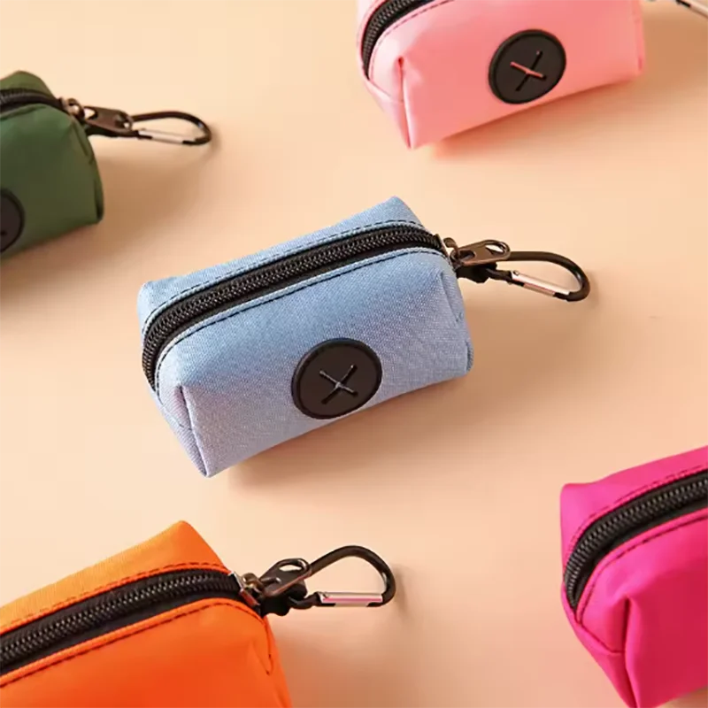 Collection de petits sacs à fermeture éclair roses, verts et bleus avec attaches à carabiner sur fond clair.