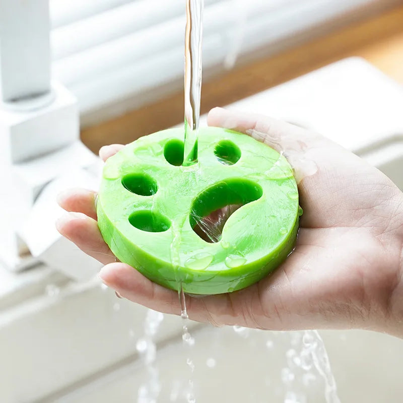 Eine Hand hält einen leuchtend grünen wiederverwendbaren Haarentferner für Haustiere mit Löchern, der Wasser tropft.