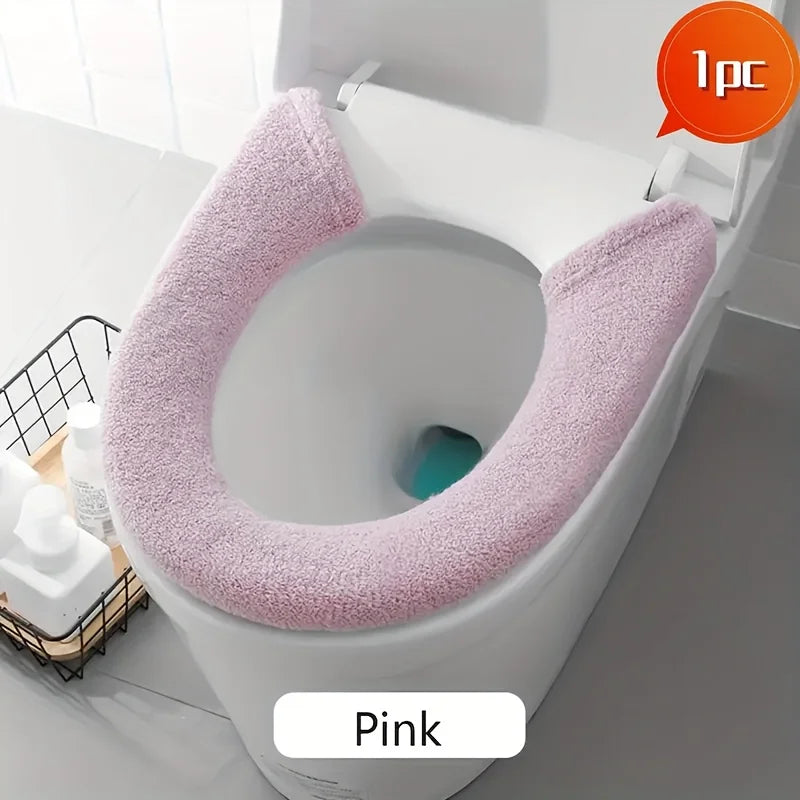 Pink plush non-slip toilet seat cover installed on a white toilet bowl.