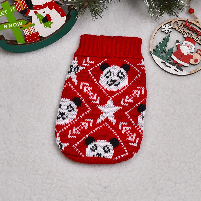 A red knitted sweater with a white pattern of panda faces and stars, displayed next to a Christmas ornament.