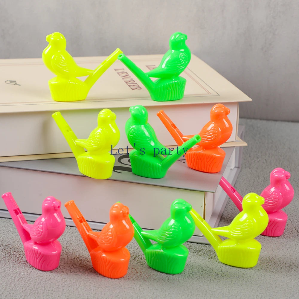 A collection of ten colorful bird and dinosaur water whistles in various bright colors arranged on a stack of books.