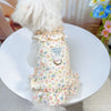 A light yellow floral summer dress for dogs or cats with ruffled trim, displayed on a white plate.
