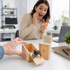 A hand is opening a wooden box containing a black spider for a surprise prank.
