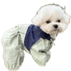 Un chien blanc et duveteux portant une combinaison imperméable vert clair.