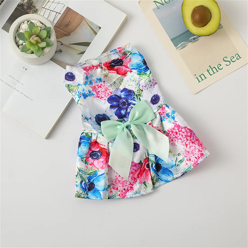 A floral print dog dress featuring pink, blue, and green flowers with a light green bow.